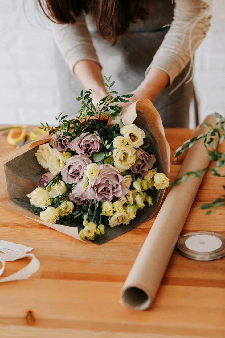 woman florist collects bouquet decorates different flowers