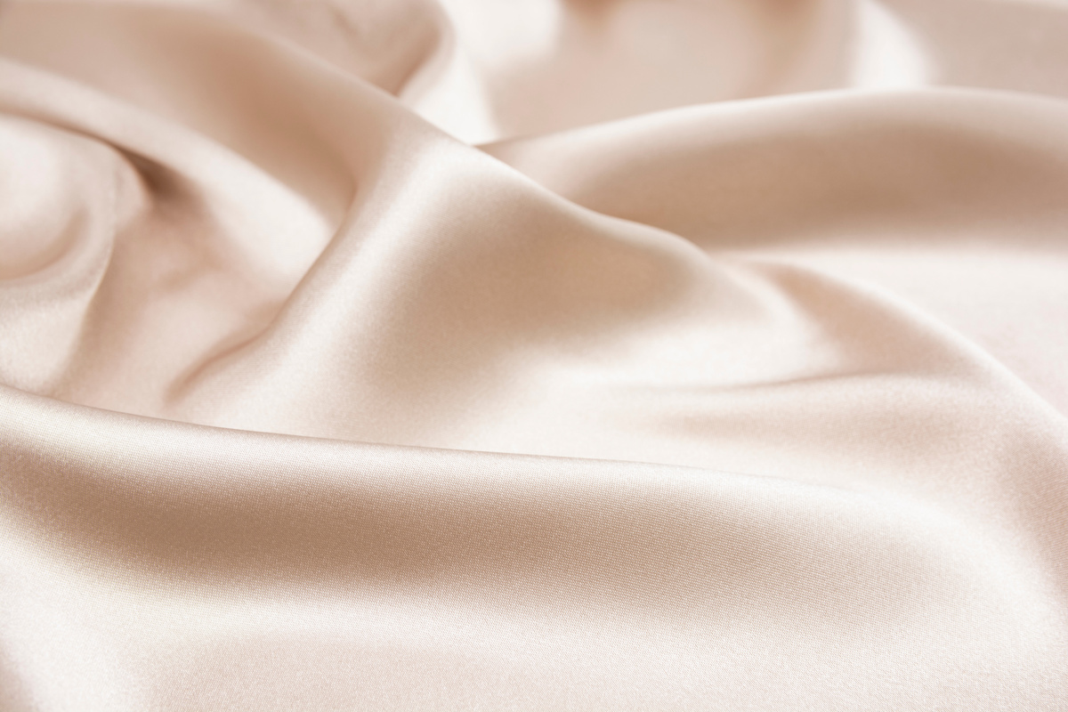 The texture of the satin fabric of beige color for the background